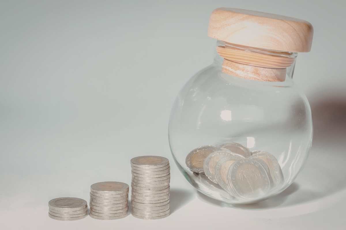 monete e un barattolo di vetro pronto ad accoglierle