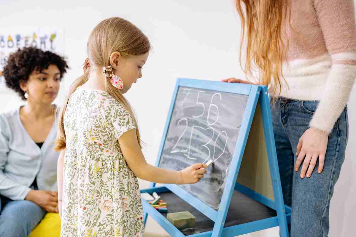 bambina scrive numeri sulla lavagna