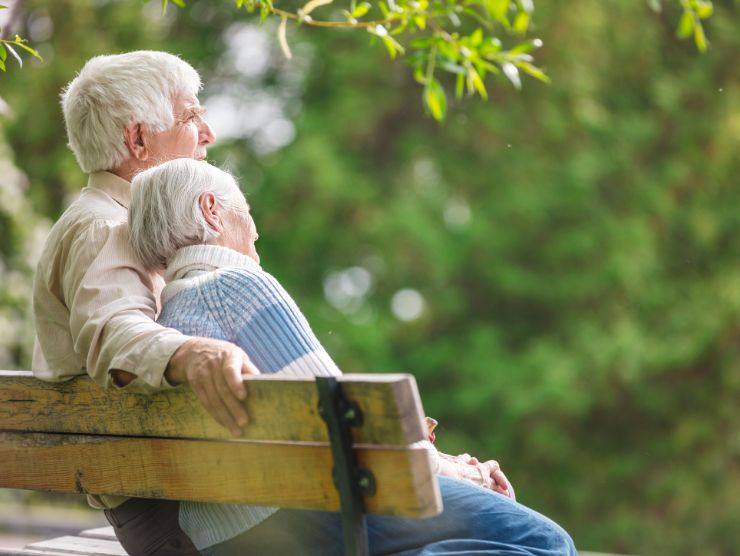 coppia di anziani seduti su una panchina in un parco
