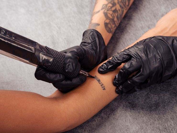 tatuatore che sta tatuando il braccio di una persona